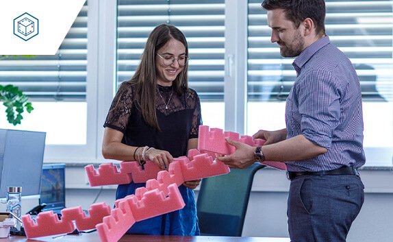 Zwei Mitarbeiter*innen besprechen das Design eines Gefaches aus Schaumstoff.