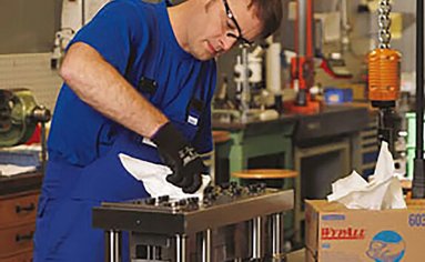 Ein Mitarbeiter säubert ein Metallteil mit einem Reinigungsmittel.
