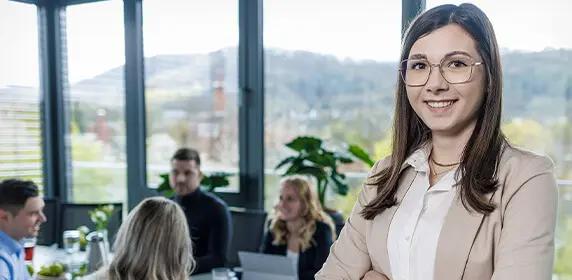 Eine Kundenbetreuerin von PRODINGER Verpackung steht vor einem Besprechungstisch.