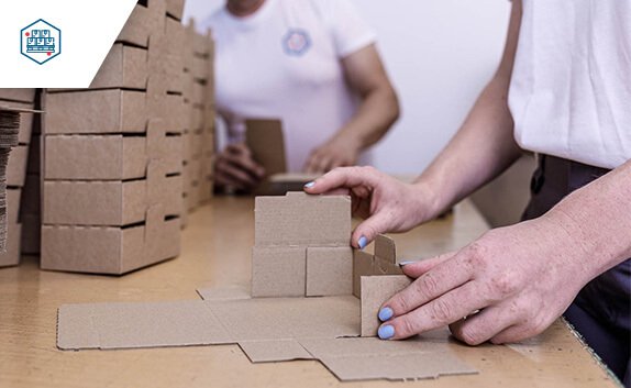 Eine Mitarbeiterin von PRODINGER Verpackung faltet kleine Kartons im Kundenauftrag.