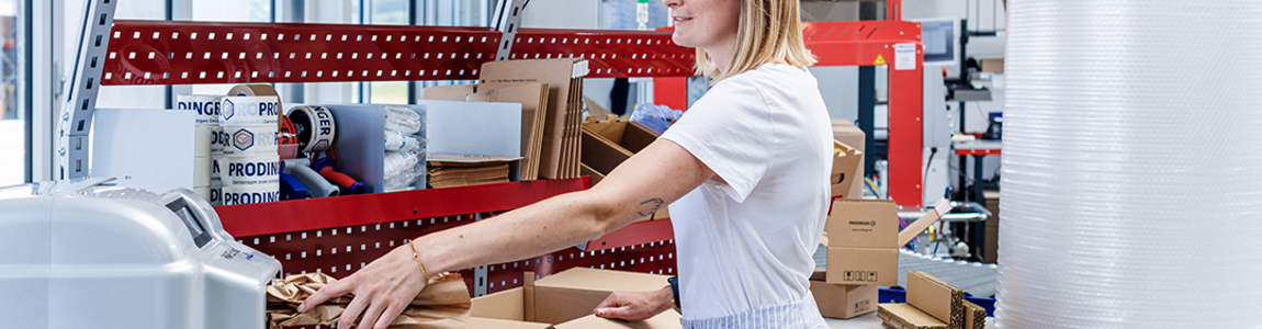 PaperBubble erzeugt Papierpolster, die in die Kartonage an einem Packtisch mit diversen Schutz- und Polstermaterialien, wie z. B. Luftpolsterfolie, zum Schutz des Produkt beigelegt werden.